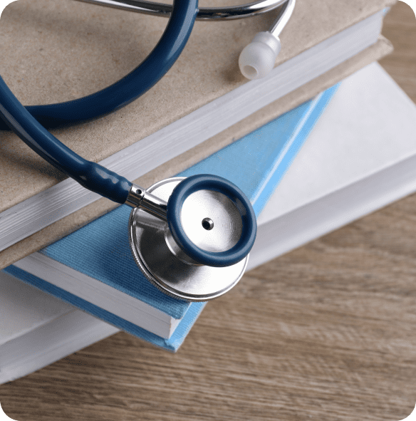 Stethoscope on stacked books, wooden table.
