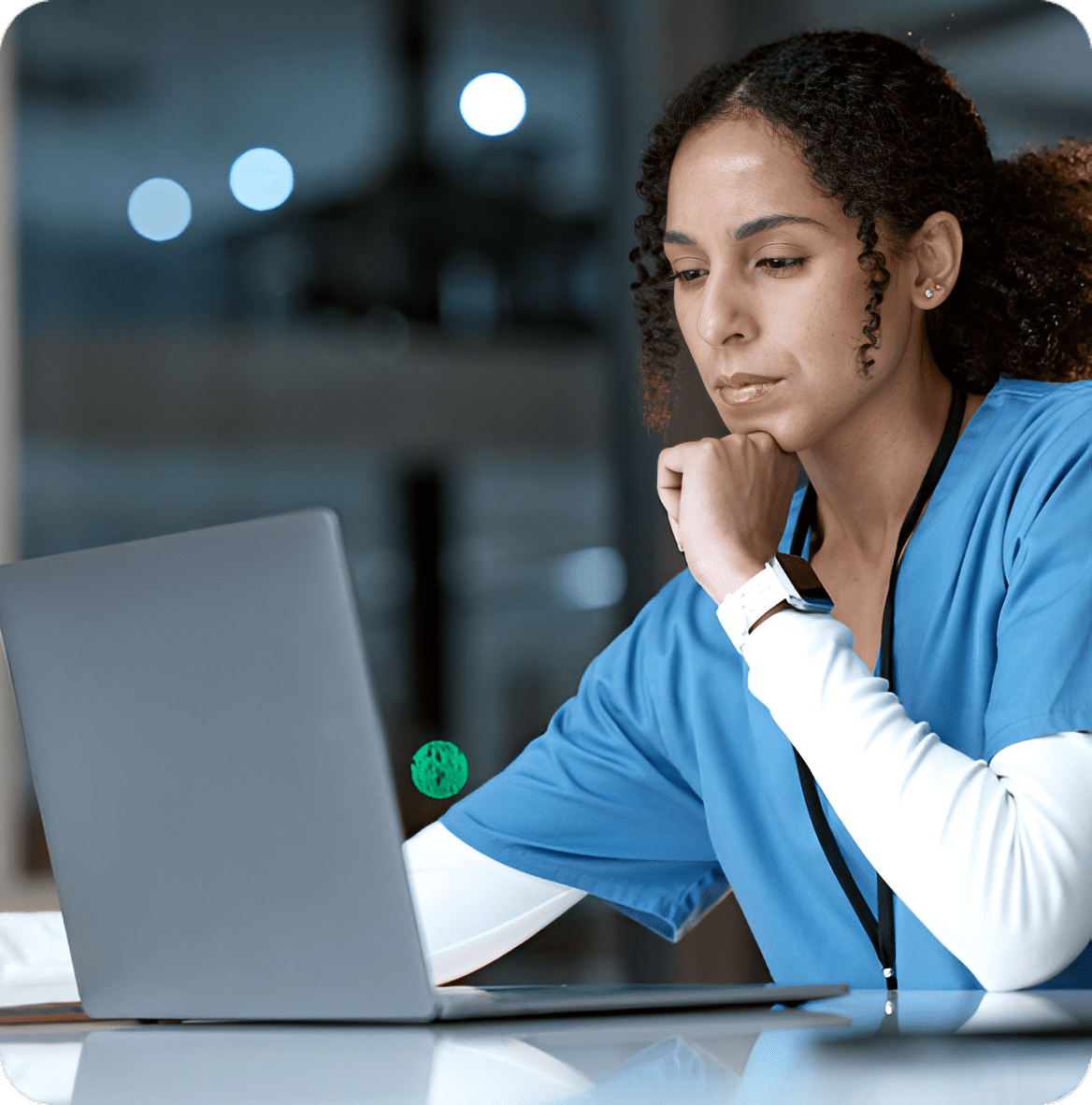 Person in scrubs working on laptop.